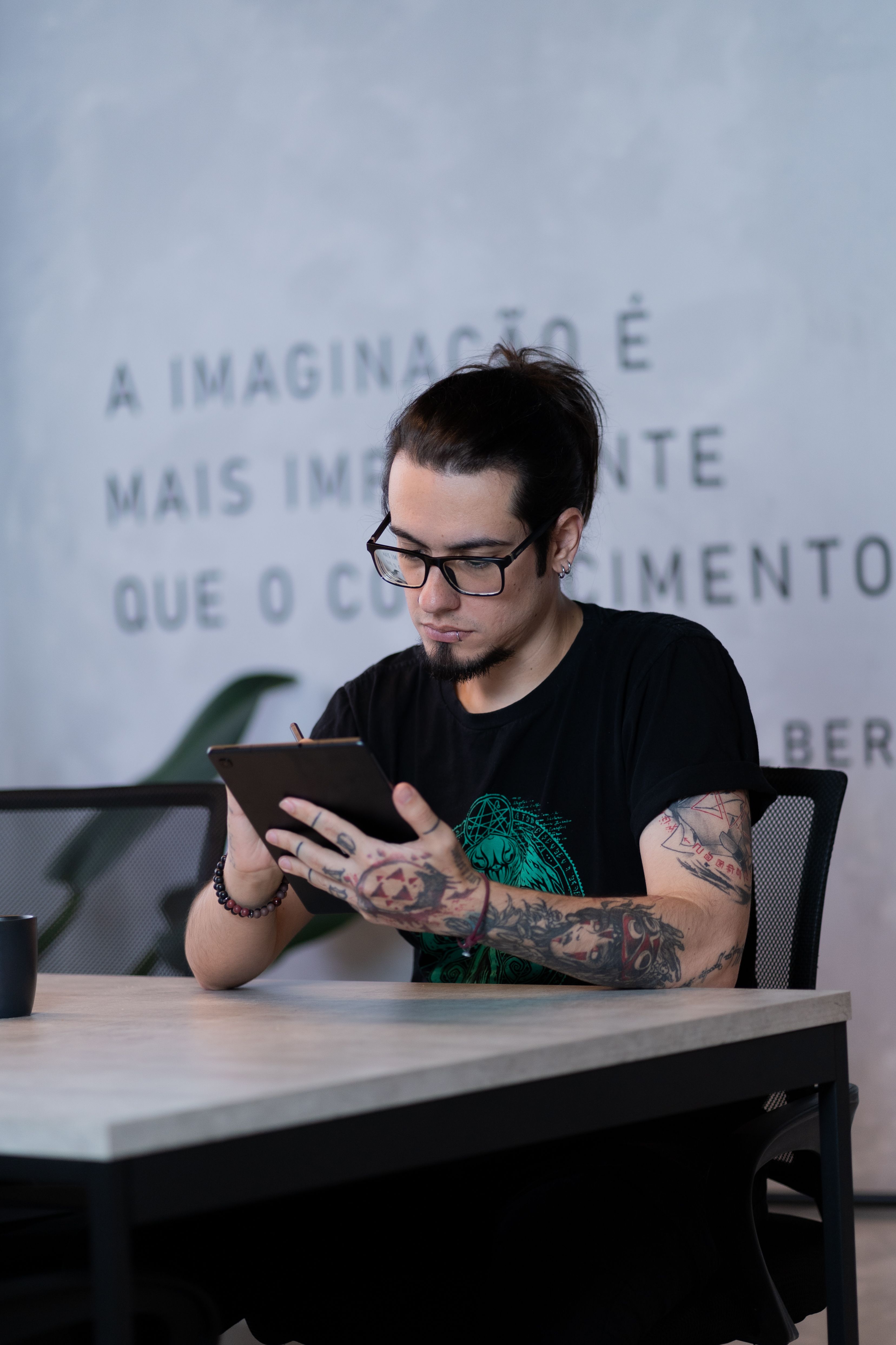 Profissional criativo com tatuagem no braço em espaço de trabalho moderno com tablet